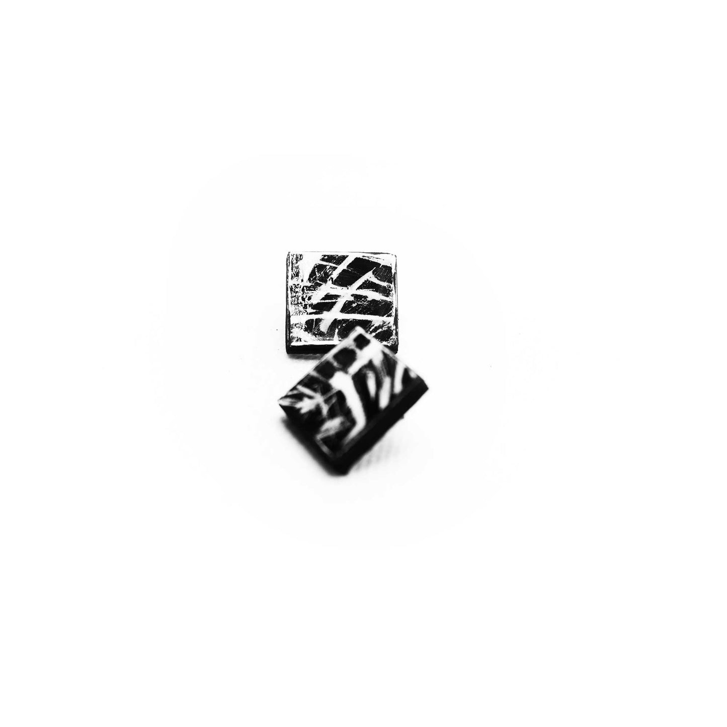 Boucles d'oreilles en liège peint à la main, formes géométriques nettes, style graphique noir et blanc.